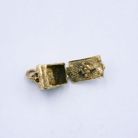 9ct yellow gold Alpine house charm with intricate detail; opens to reveal a family of four around a table inside; approx. 10mm high by 8mm wide, weighing 3.6g.