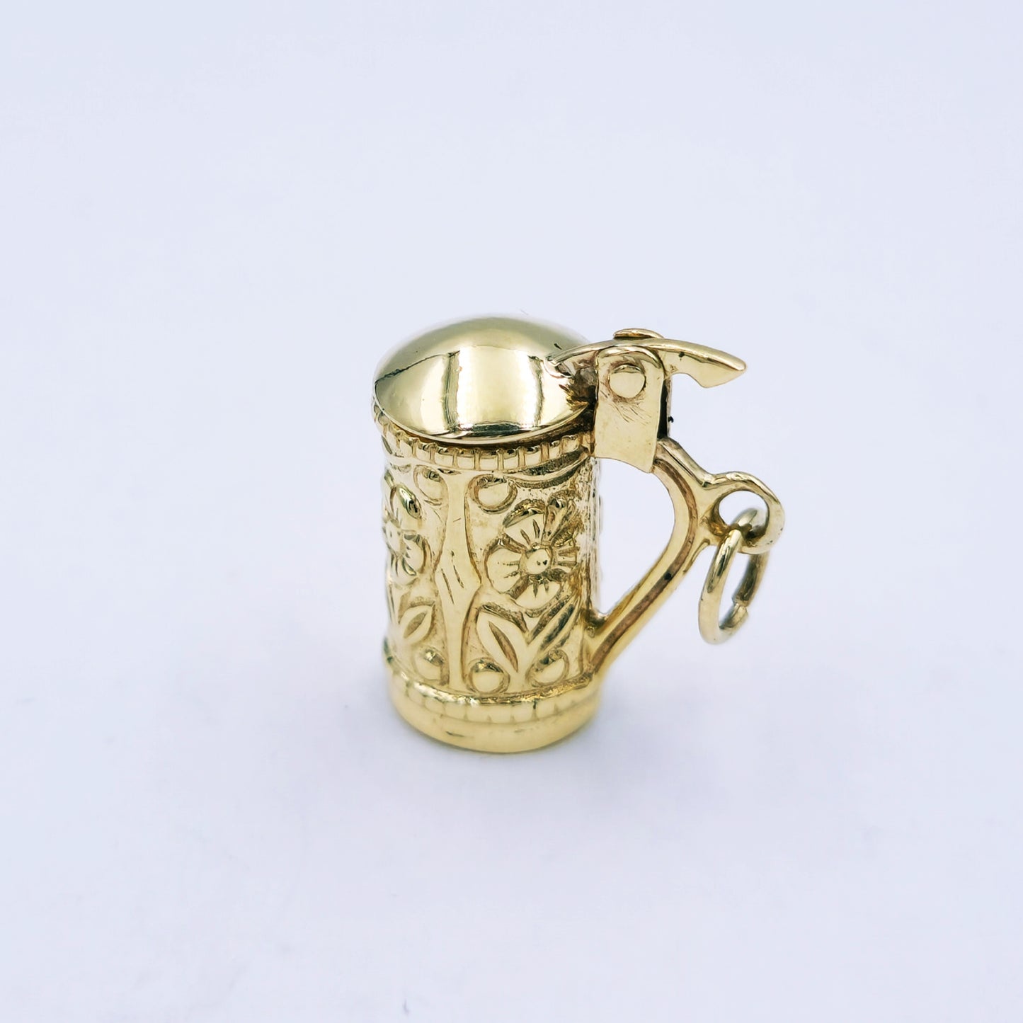 9ct yellow gold beer mug charm with floral design and hinged lid that opens; approx. 16.5mm high by 8mm wide, weighing 3.7g.