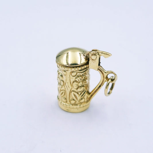9ct yellow gold beer mug charm with floral design and hinged lid that opens; approx. 16.5mm high by 8mm wide, weighing 3.7g.