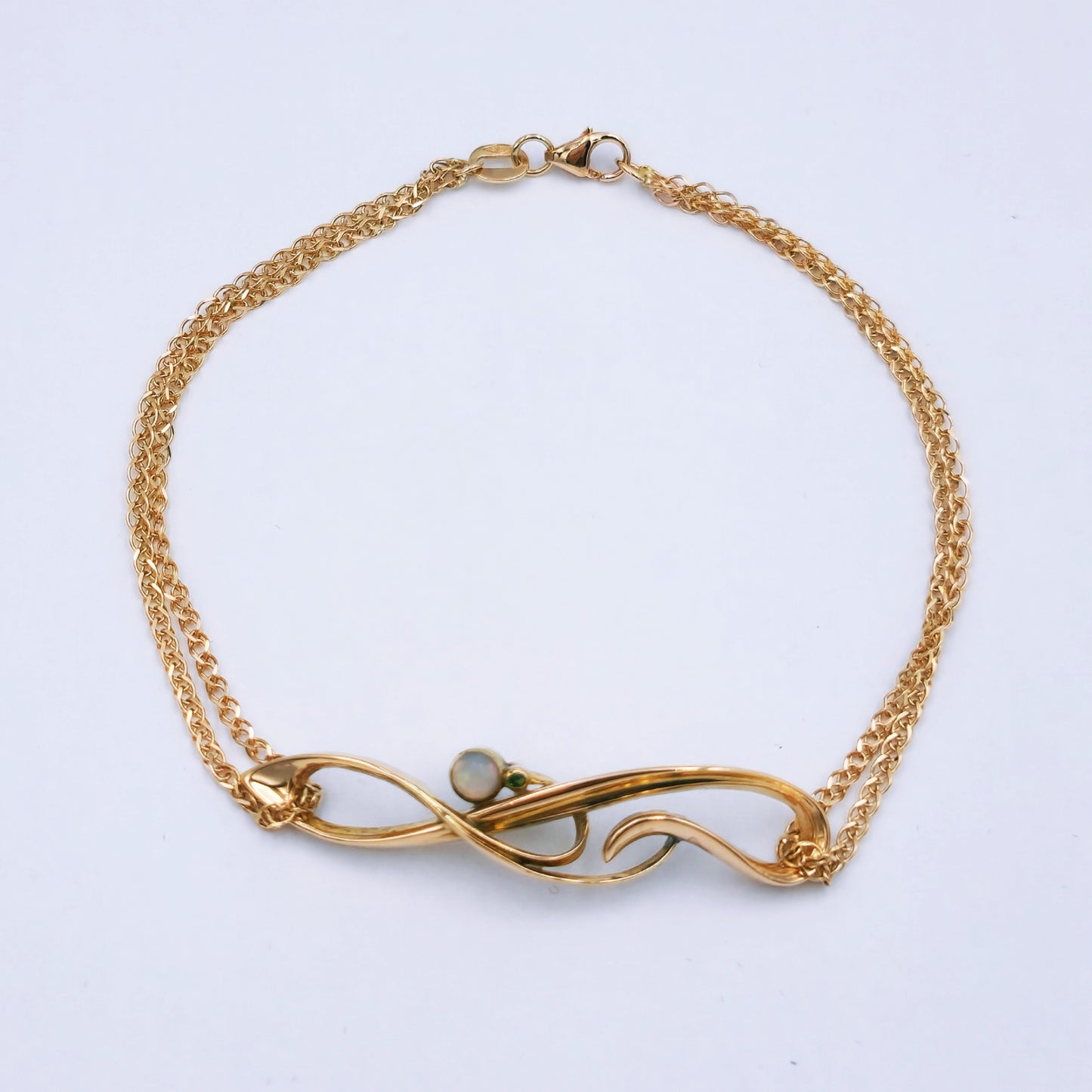 Restored Art Deco bracelet with 15ct rose gold panel set with a 3.5mm opal and 0.01ct emerald, attached to a delicate double strand 9ct rose gold chain; 19.5cm long, approx. 3.9g.