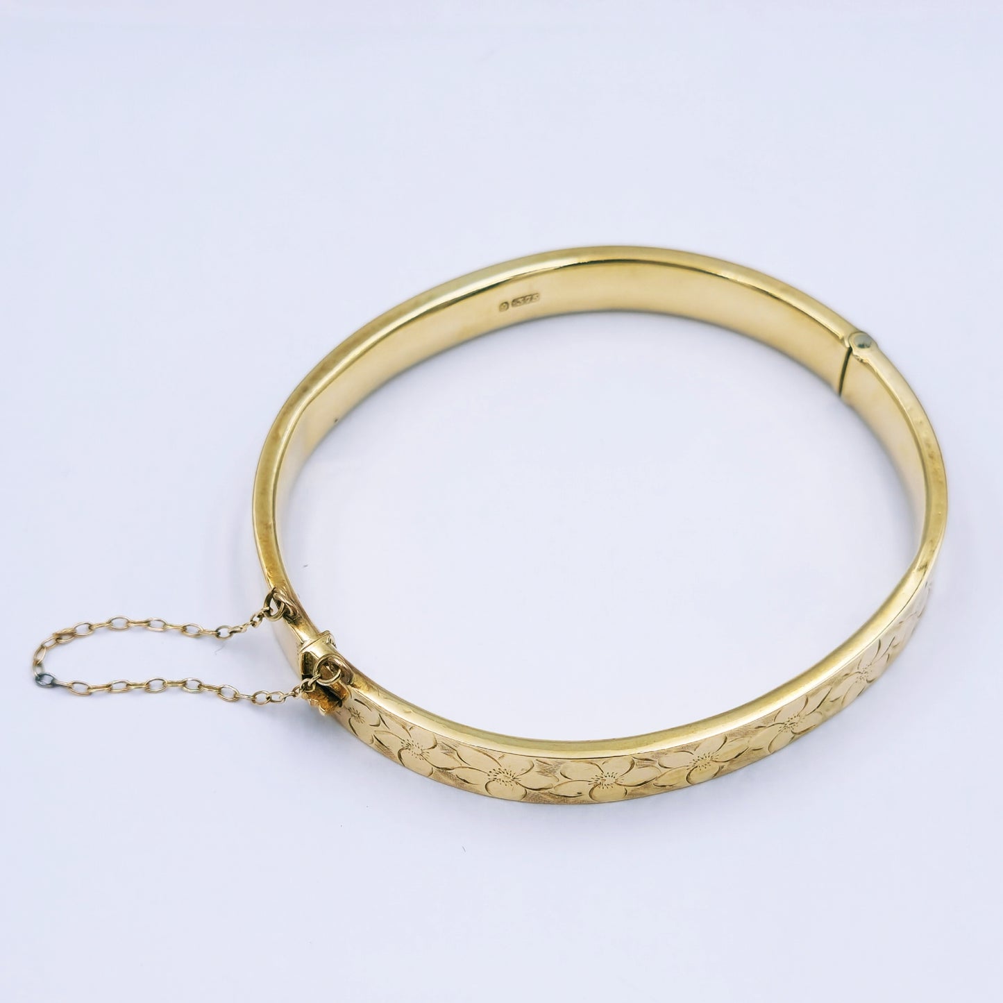 Vintage 9ct yellow gold hinged bracelet with daisy engraving on top, 7.5mm wide with oval diameter approx. 5.3cm x 5.9cm, tight clasp and safety chain; 10.72g