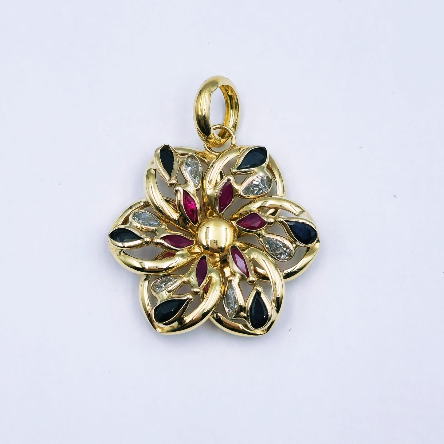 9ct yellow gold flower pendant with clear, red, and blue cubic zirconia stones and a large loop; approx. 2.9cm diameter and 4.3g in weight.