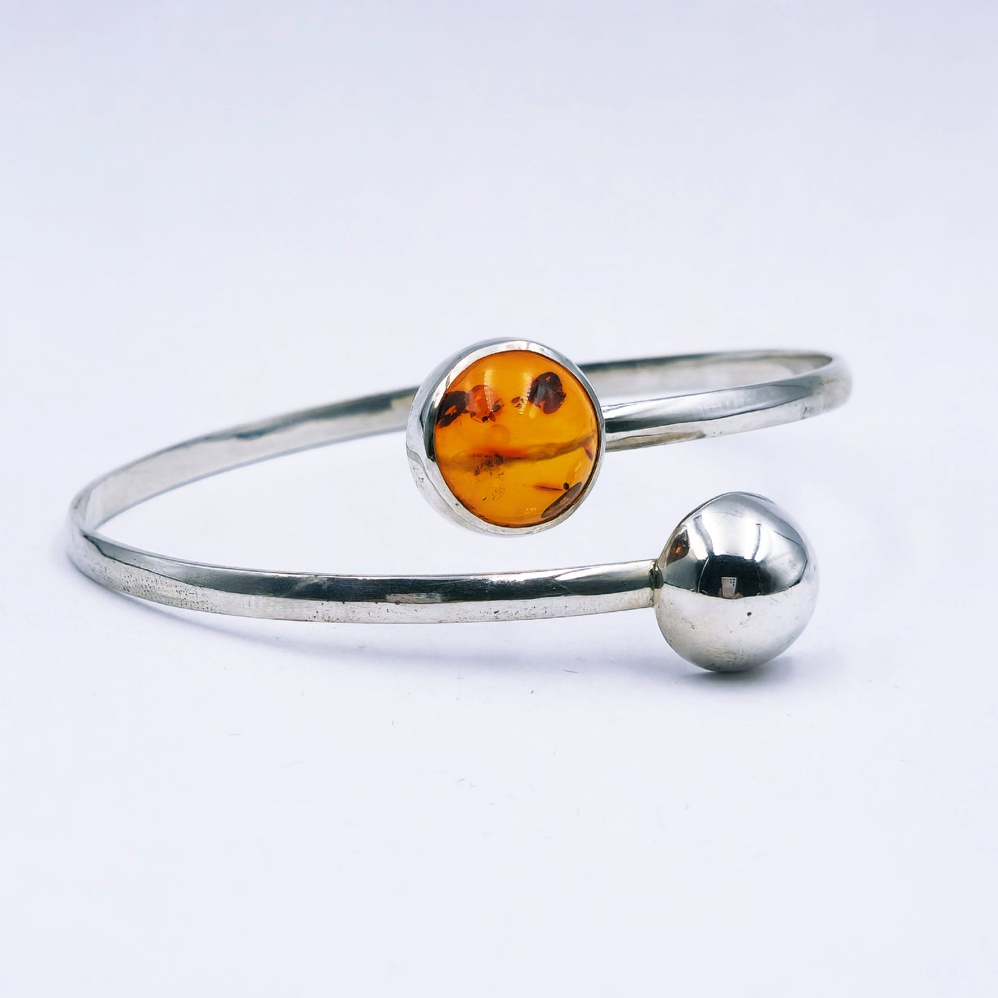 Handmade sterling silver split bangle with amber cabochon in tube setting and silver half dome detail,