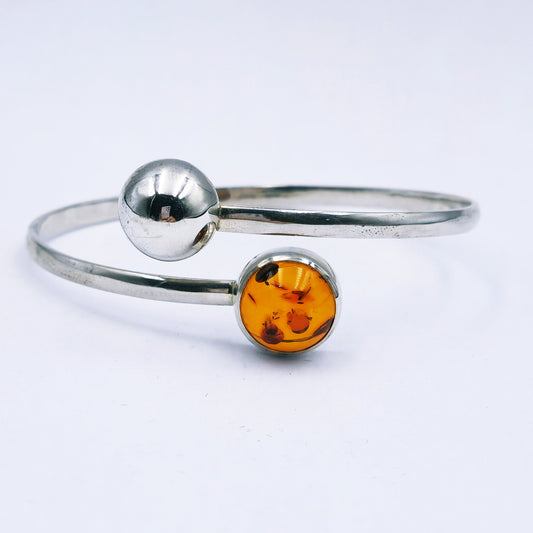 Handmade sterling silver split bangle with amber cabochon in tube setting and silver half dome detail,