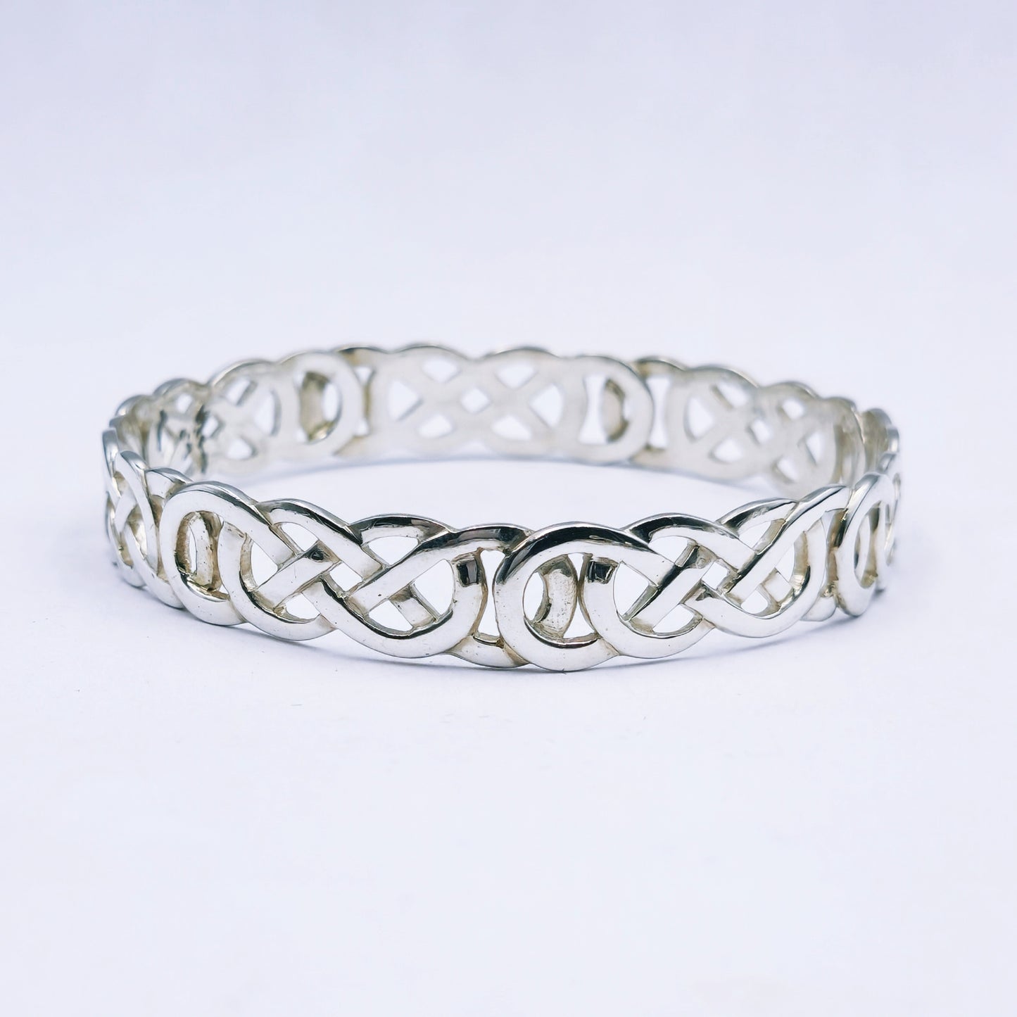Silver bracelet with intricate Celtic knot design on a white background