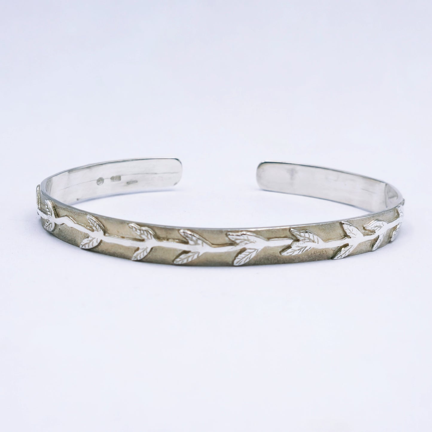 Handcrafted sterling silver C-shape bangle with matte finish and leaf and stalk design, 65mm diameter and 8mm width.