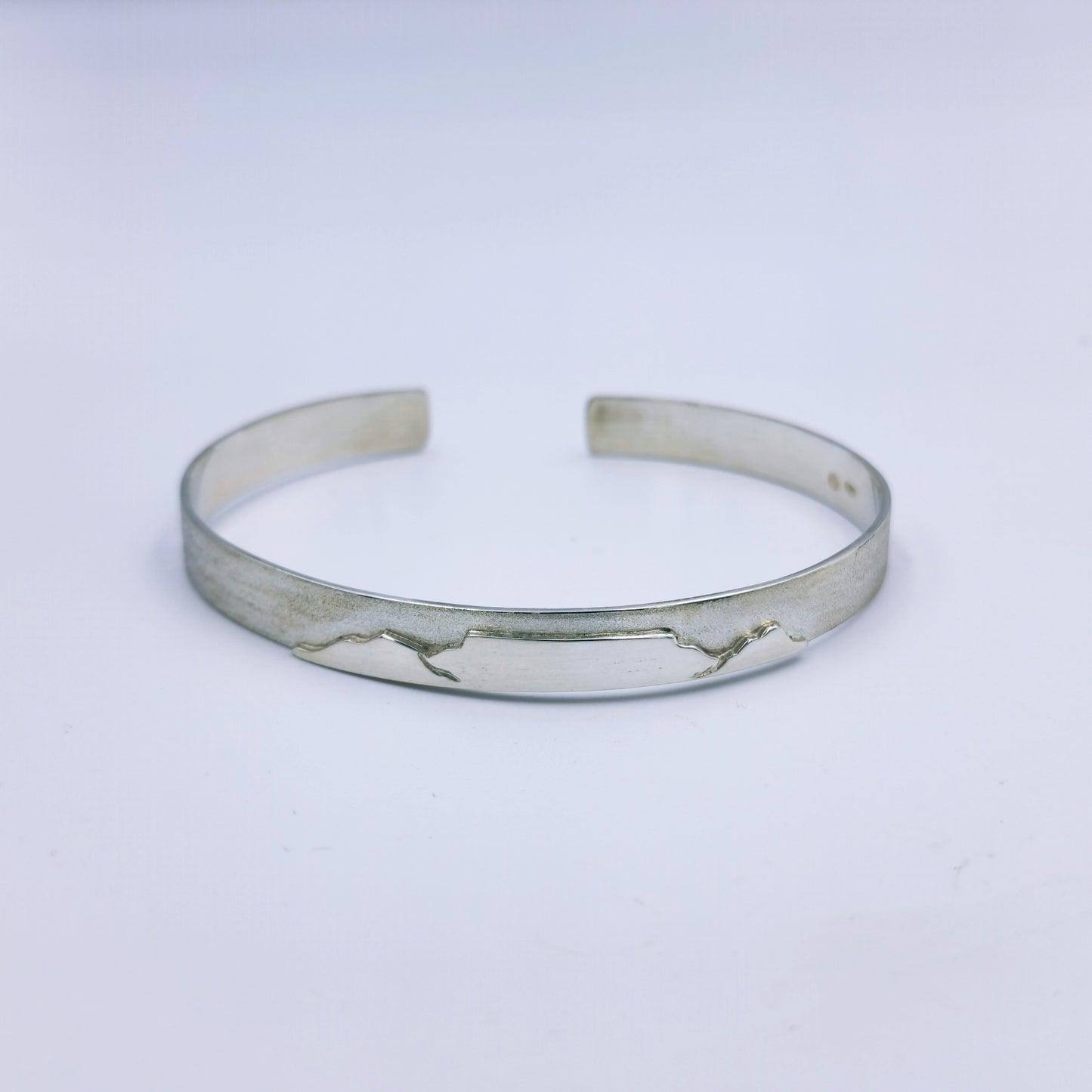 Men’s handmade sterling silver flat bangle with matte finish and Table Mountain motif, C-shaped, 70mm diameter and 7.5mm width.