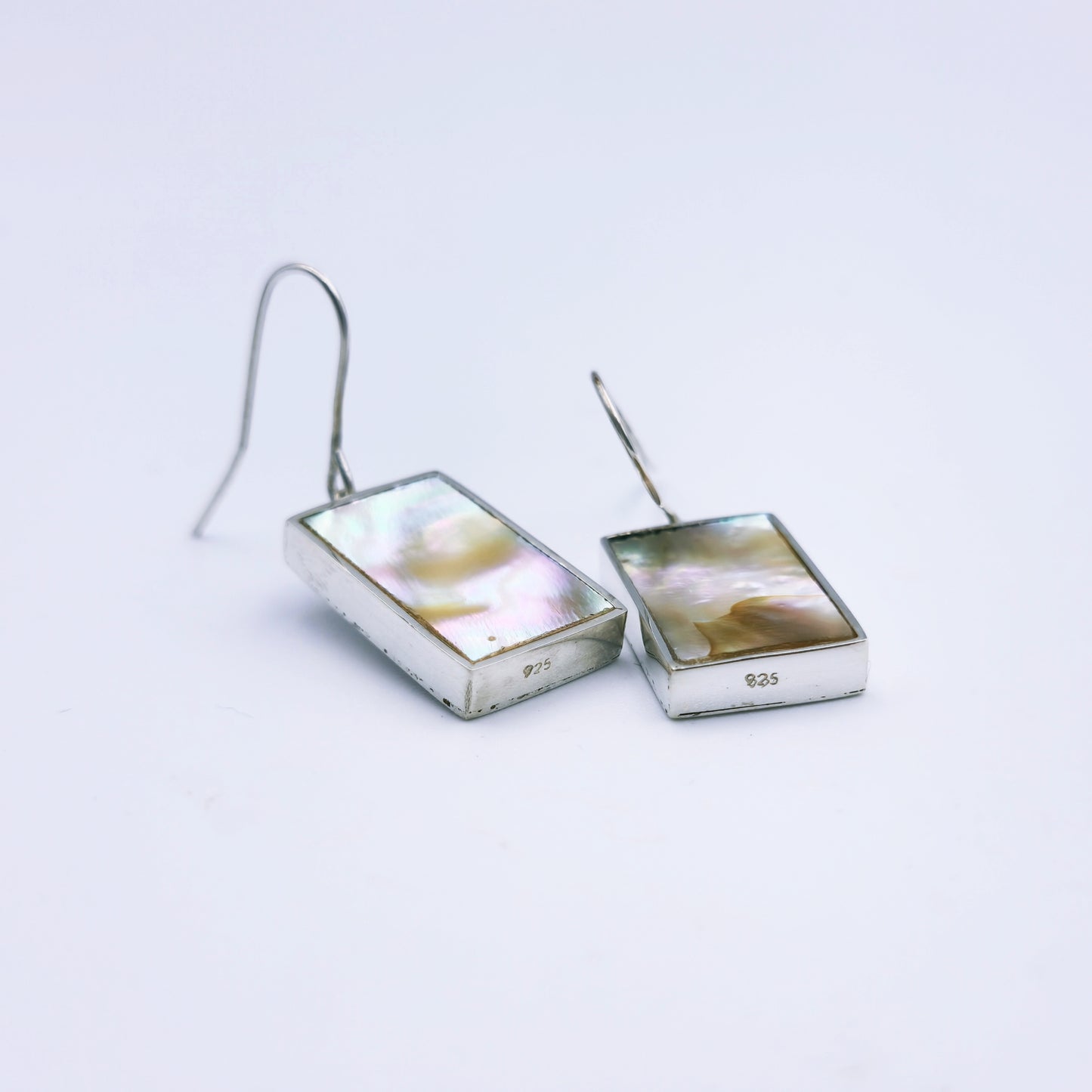 Sterling silver abalone earrings with blue and pink/grey peacock tones, set in rectangular frames and hanging from shepherd hooks.