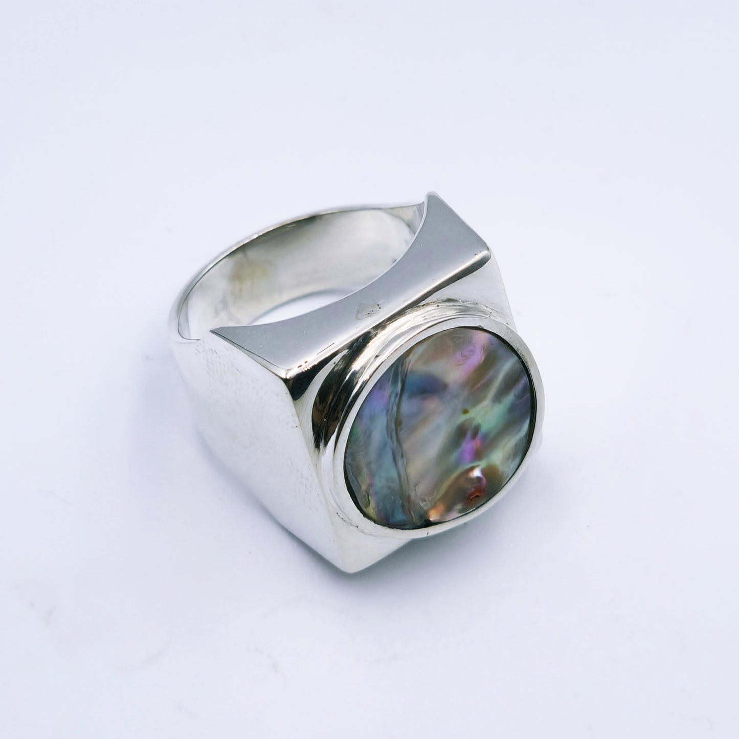 Free-form sterling silver pendant with natural abalone shell from the Eastern Cape, showing iridescent blues and greens with a silver frame.