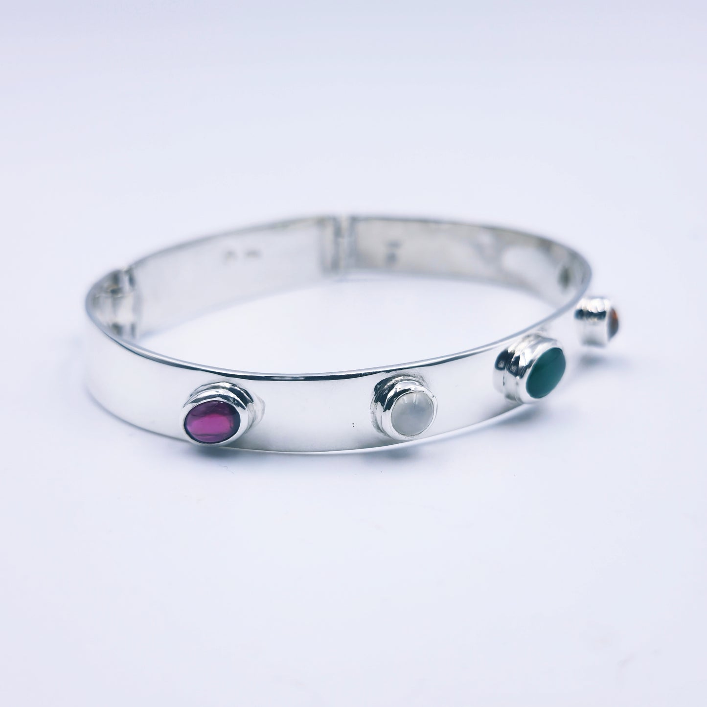Sterling silver bangle with sky blue topaz, citrine, amethyst, peridot, and garnet in assorted cuts on a half-round band.