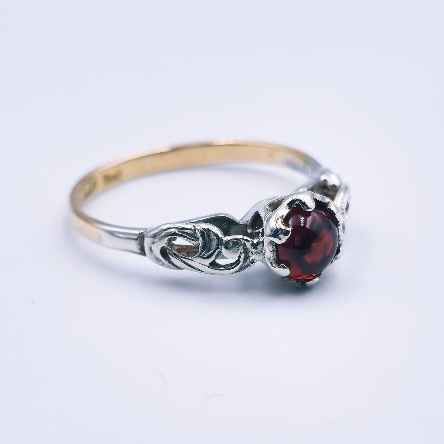 Two-toned 9ct gold ring with a 6mm cabochon cut garnet and detailed white gold accents.