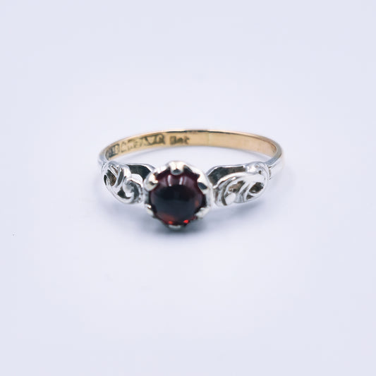 Two-toned 9ct gold ring with a 6mm cabochon cut garnet and detailed white gold accents.