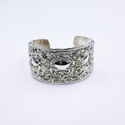 Close-up image of an antique sterling silver cuff bangle featuring ornate engraved detailing, 4cm wide, oval-shaped (70mm x 53mm), weighing approximately 44.5g.