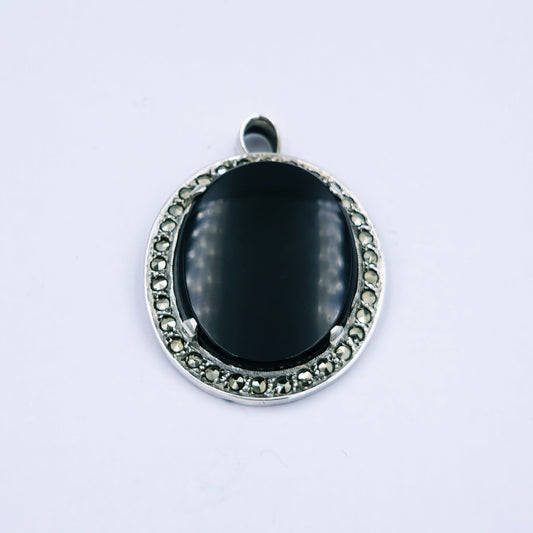 Vintage sterling silver oval pendant featuring a black onyx stone framed by a marcasite halo, approx. 3cm x 2.5cm, weighing around 6.5g