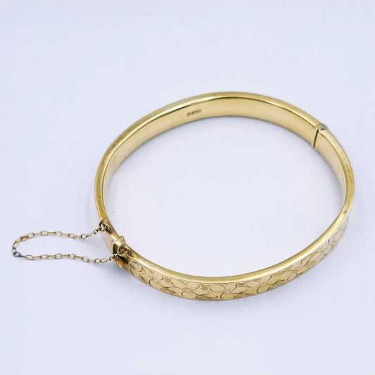 Vintage 9ct yellow gold hinged bracelet with daisy engraving on top, 7.5mm wide with oval diameter approx. 5.3cm x 5.9cm, tight clasp and safety chain; 10.72g