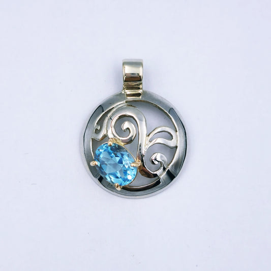 Two-tone pendant with a 21mm 9ct white gold dome featuring a twirl design and an oval 9mm x 7mm sky blue topaz set in a yellow gold four-claw setting; approx. 3.37g.