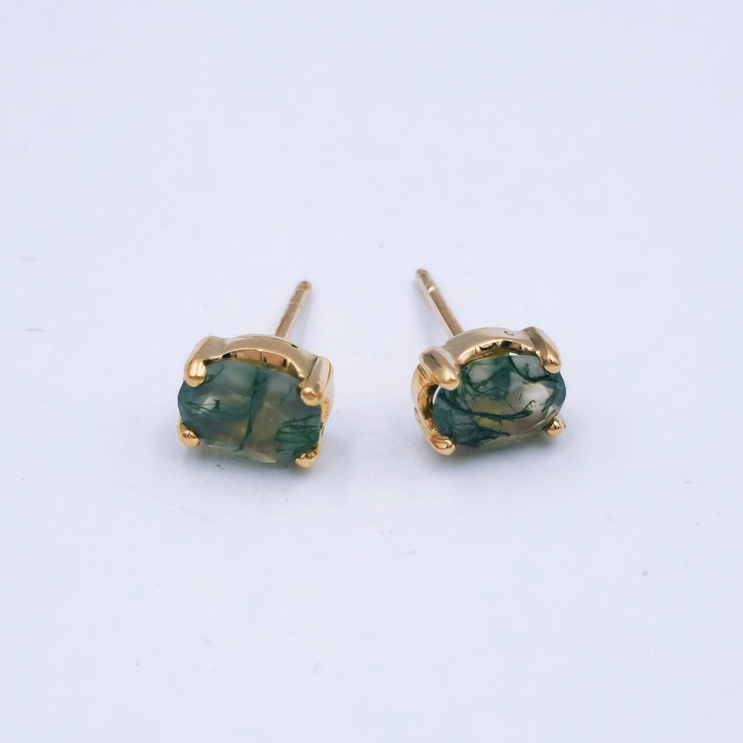 Pair of 9ct rose gold stud earrings featuring oval moss agate stones (7mm x 8mm) with soft green and moss-like inclusions, in classic four-claw settings.