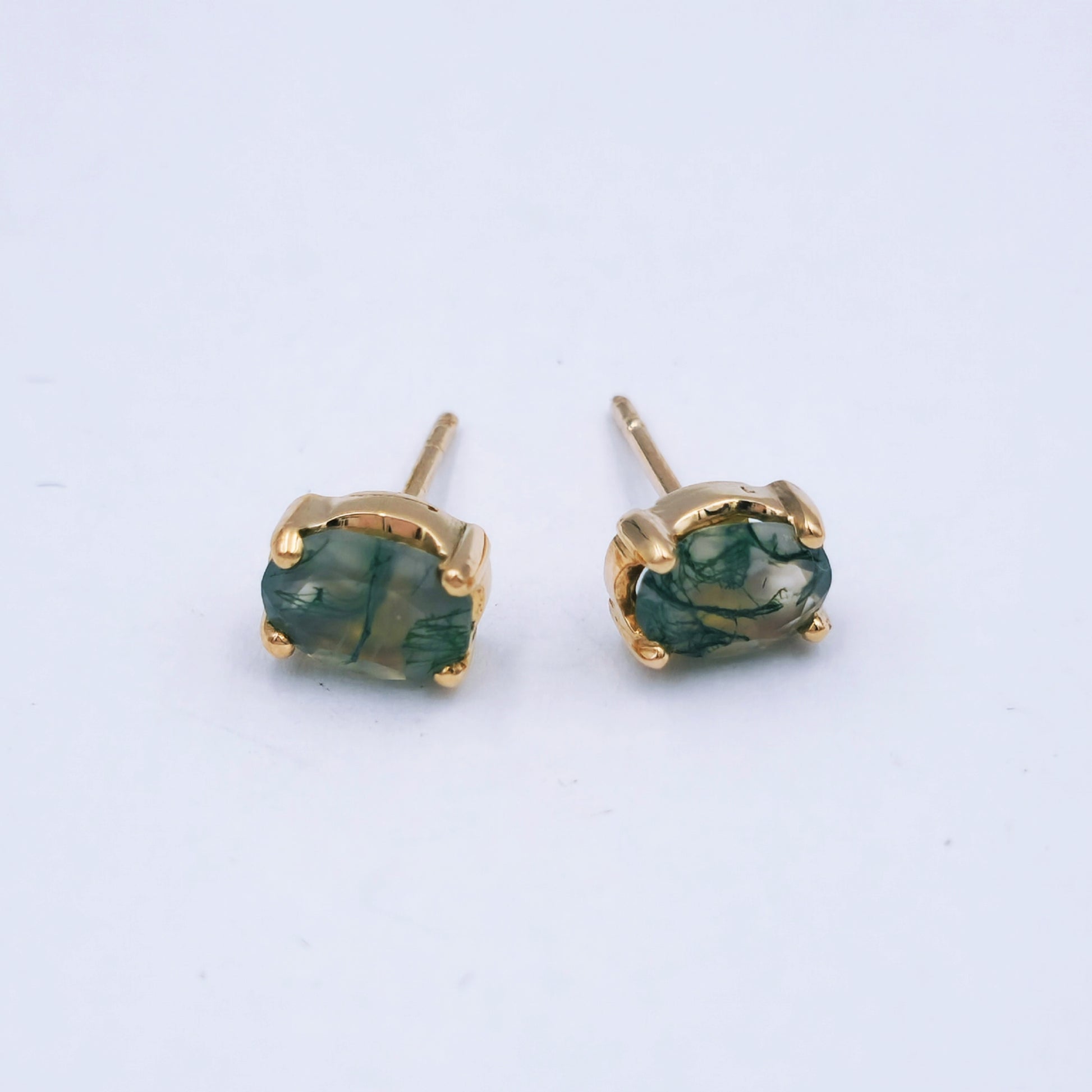 Pair of 9ct rose gold stud earrings featuring oval moss agate stones (7mm x 8mm) with soft green and moss-like inclusions, in classic four-claw settings.