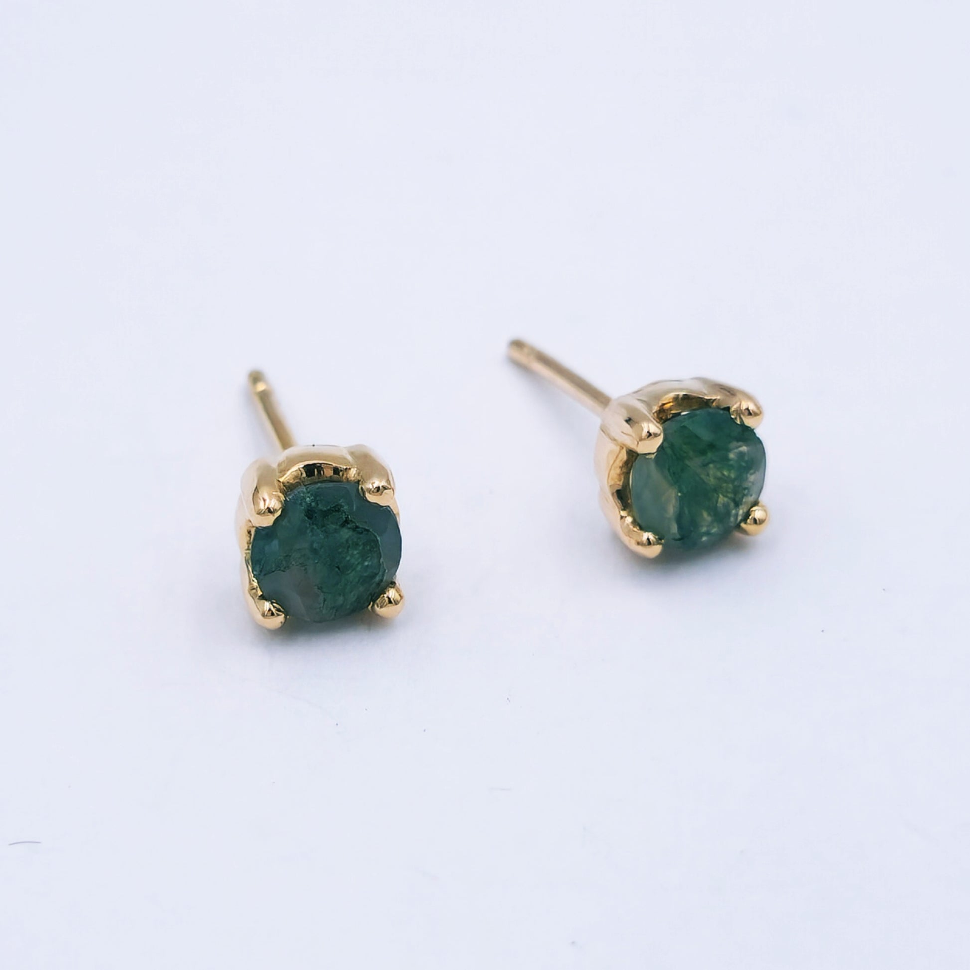 Pair of 9ct rose gold stud earrings featuring oval moss agate stones (7mm x 8mm) with soft green and moss-like inclusions, in classic four-claw settings.