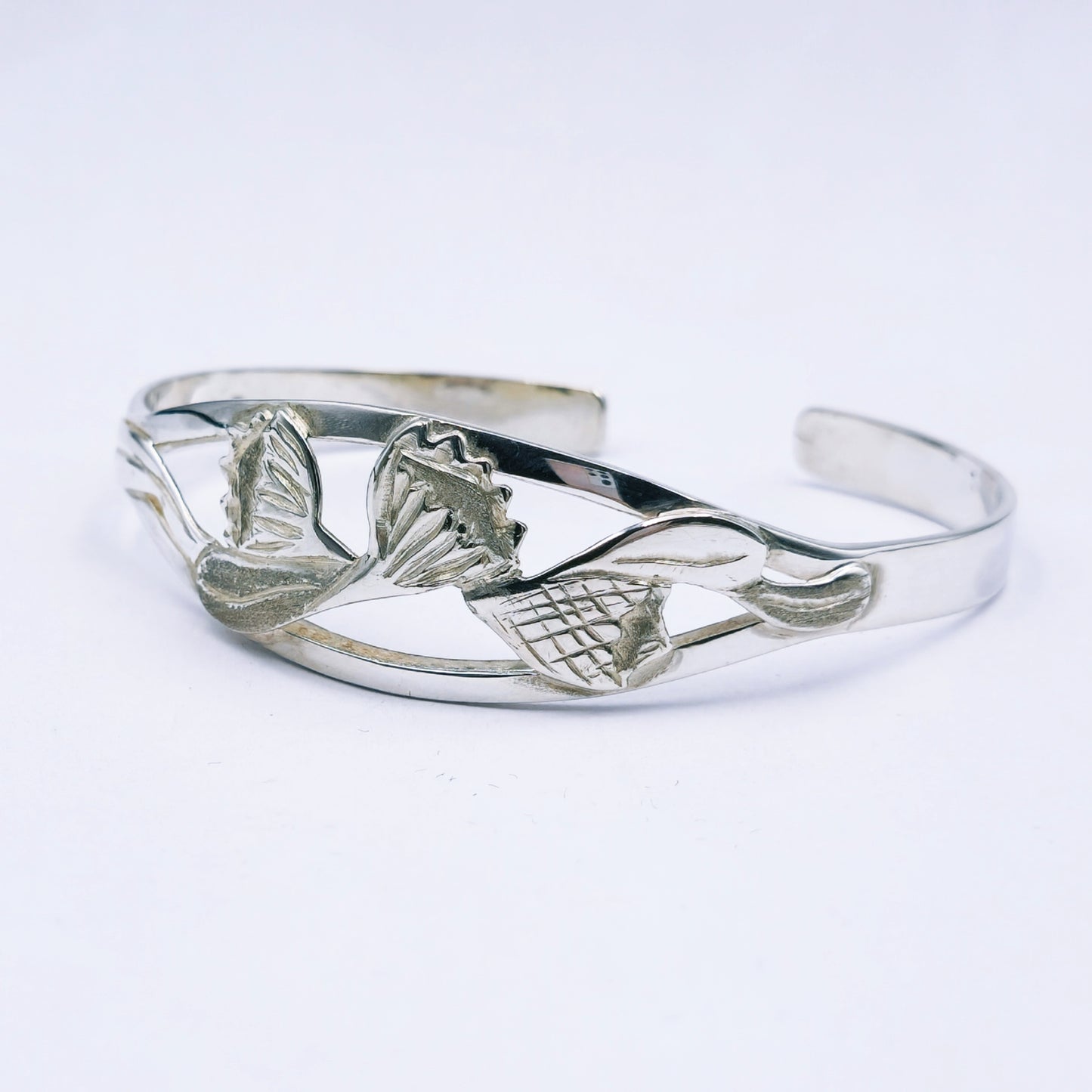 Silver bracelet with protea design on a white background