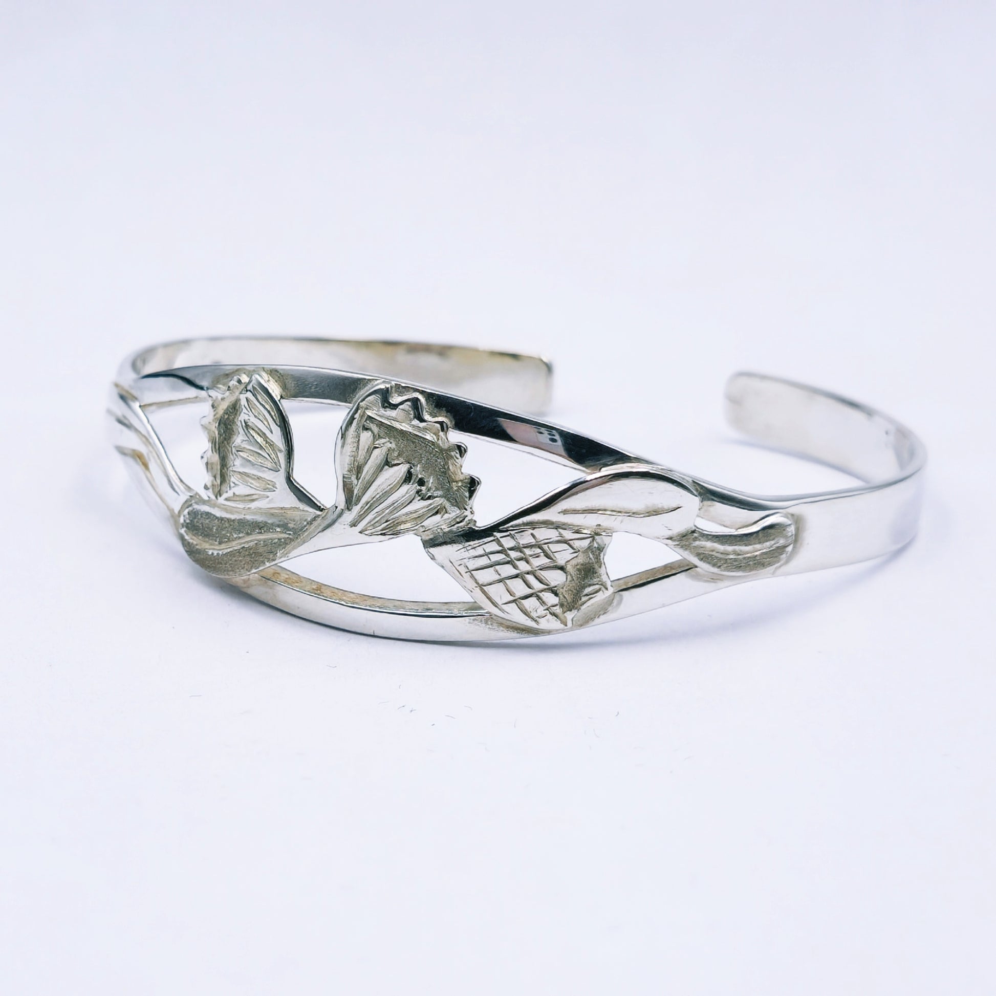Silver bracelet with protea design on a white background
