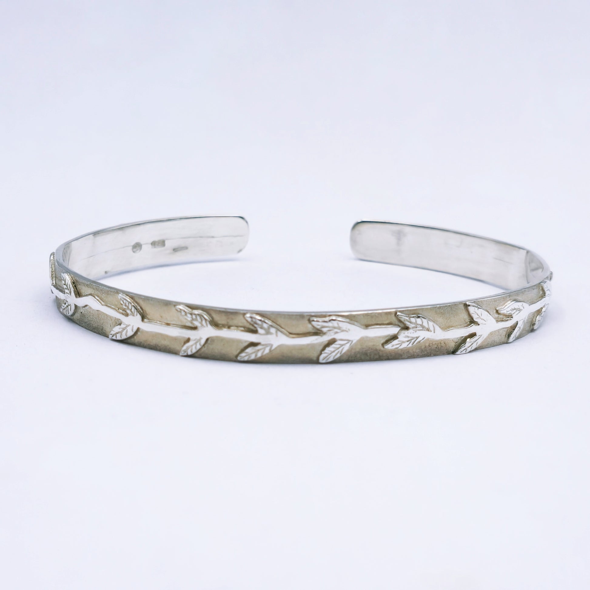 Handcrafted sterling silver C-shape bangle with matte finish and leaf and stalk design, 65mm diameter and 8mm width.