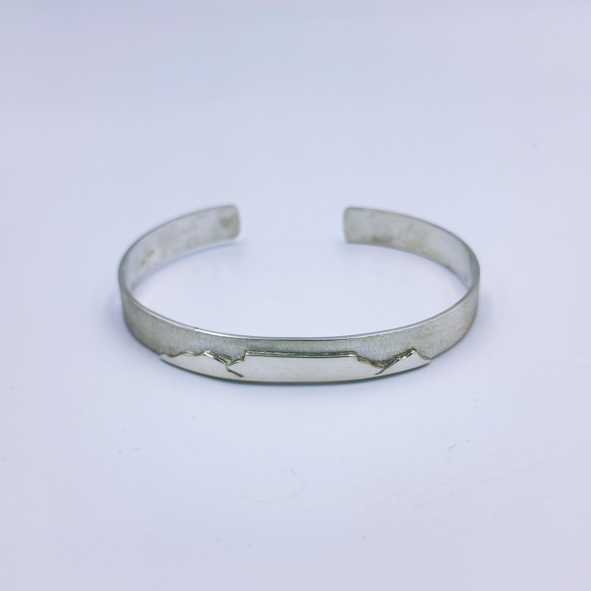 Ladies handmade sterling silver C-shaped bangle with Table Mountain motif and matte finish, 66mm diameter, 8mm wide