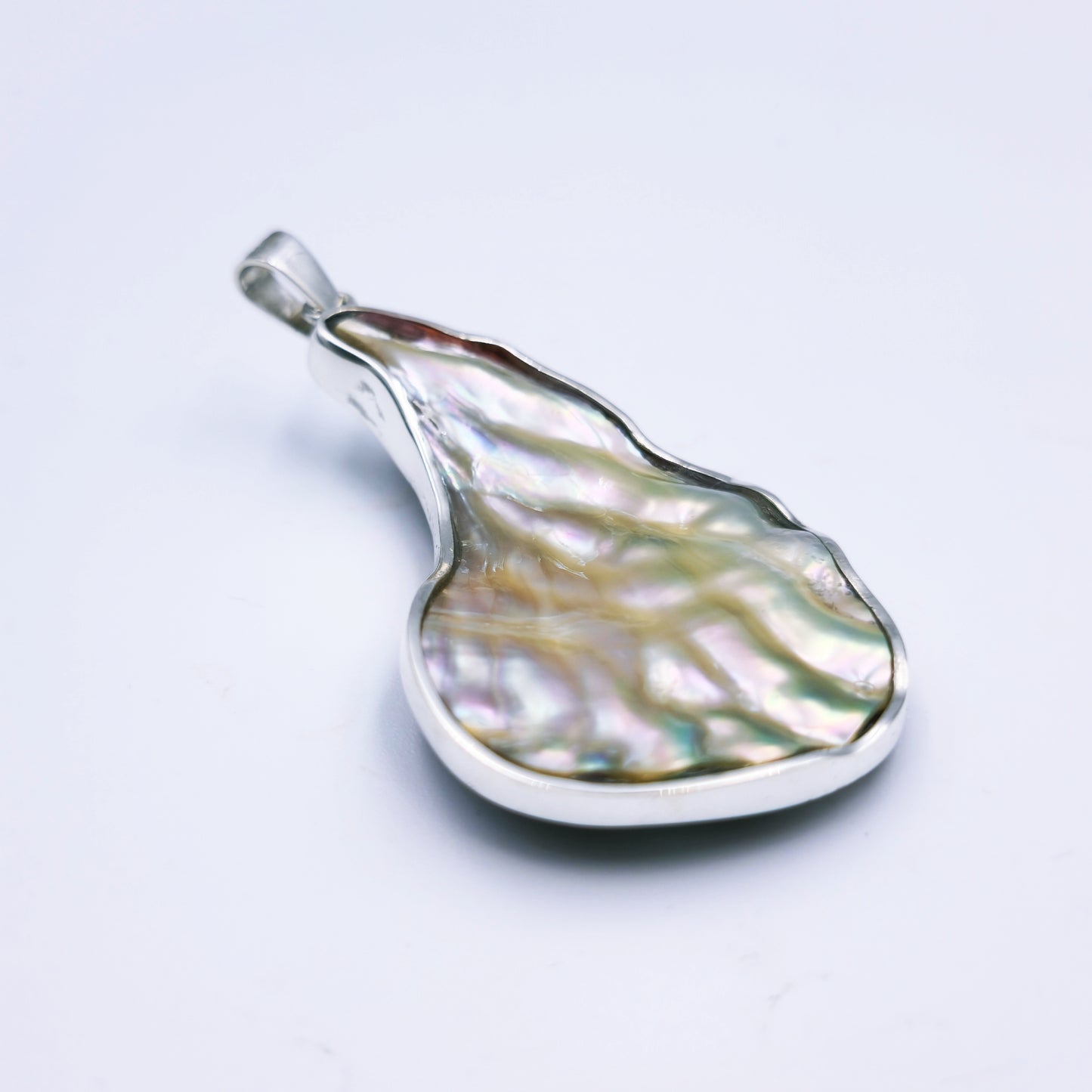 Free-form sterling silver pendant with natural abalone shell from the Eastern Cape, showing iridescent blues and greens with a silver frame.