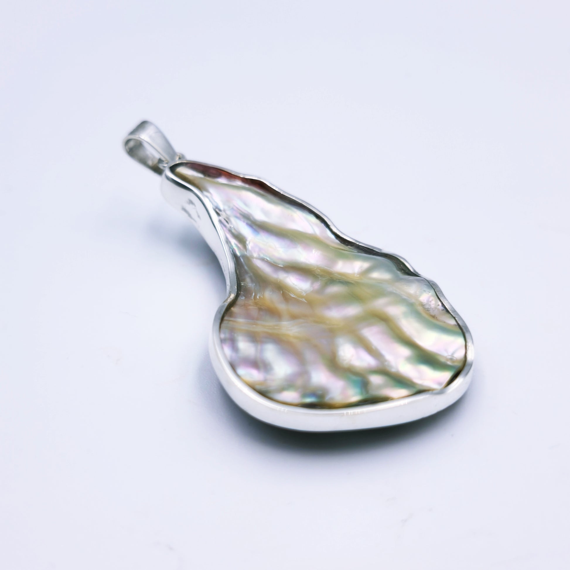 Free-form sterling silver pendant with natural abalone shell from the Eastern Cape, showing iridescent blues and greens with a silver frame.