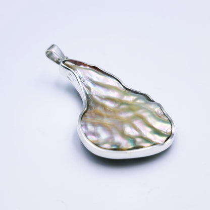 Free-form sterling silver pendant with natural abalone shell from the Eastern Cape, showing iridescent blues and greens with a silver frame.