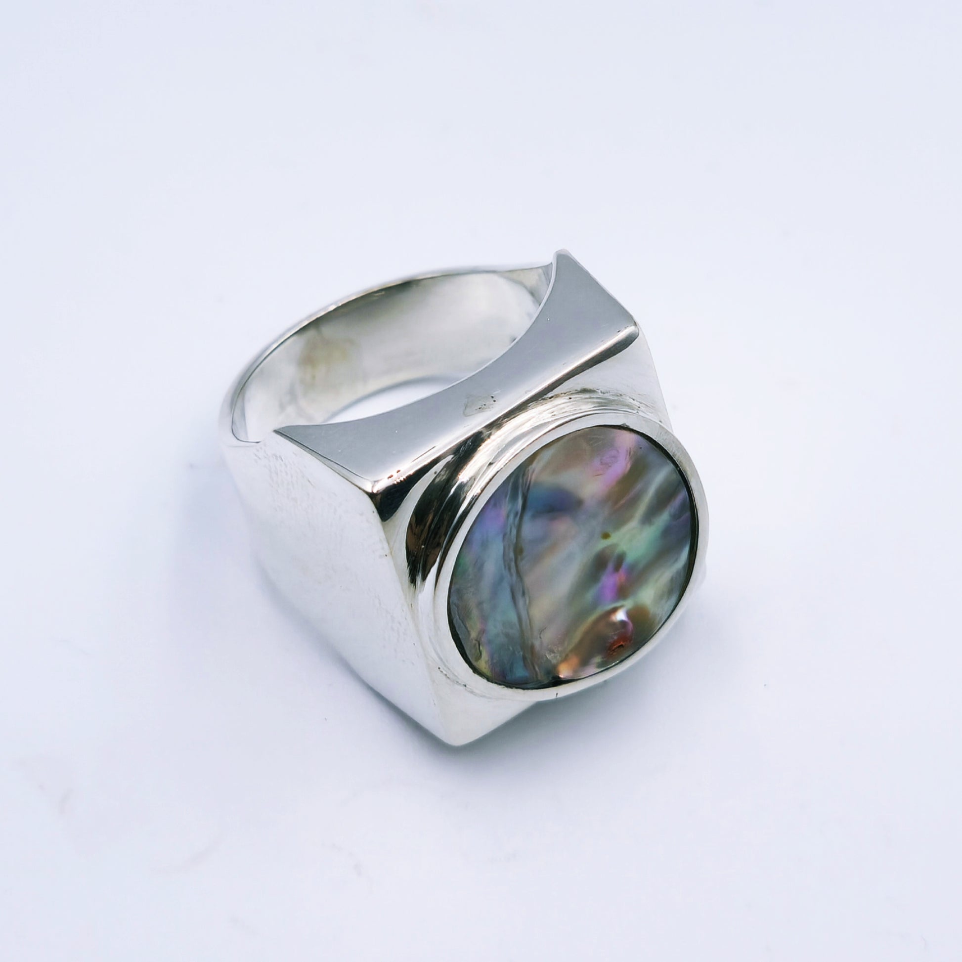 Free-form sterling silver pendant with natural abalone shell from the Eastern Cape, showing iridescent blues and greens with a silver frame.