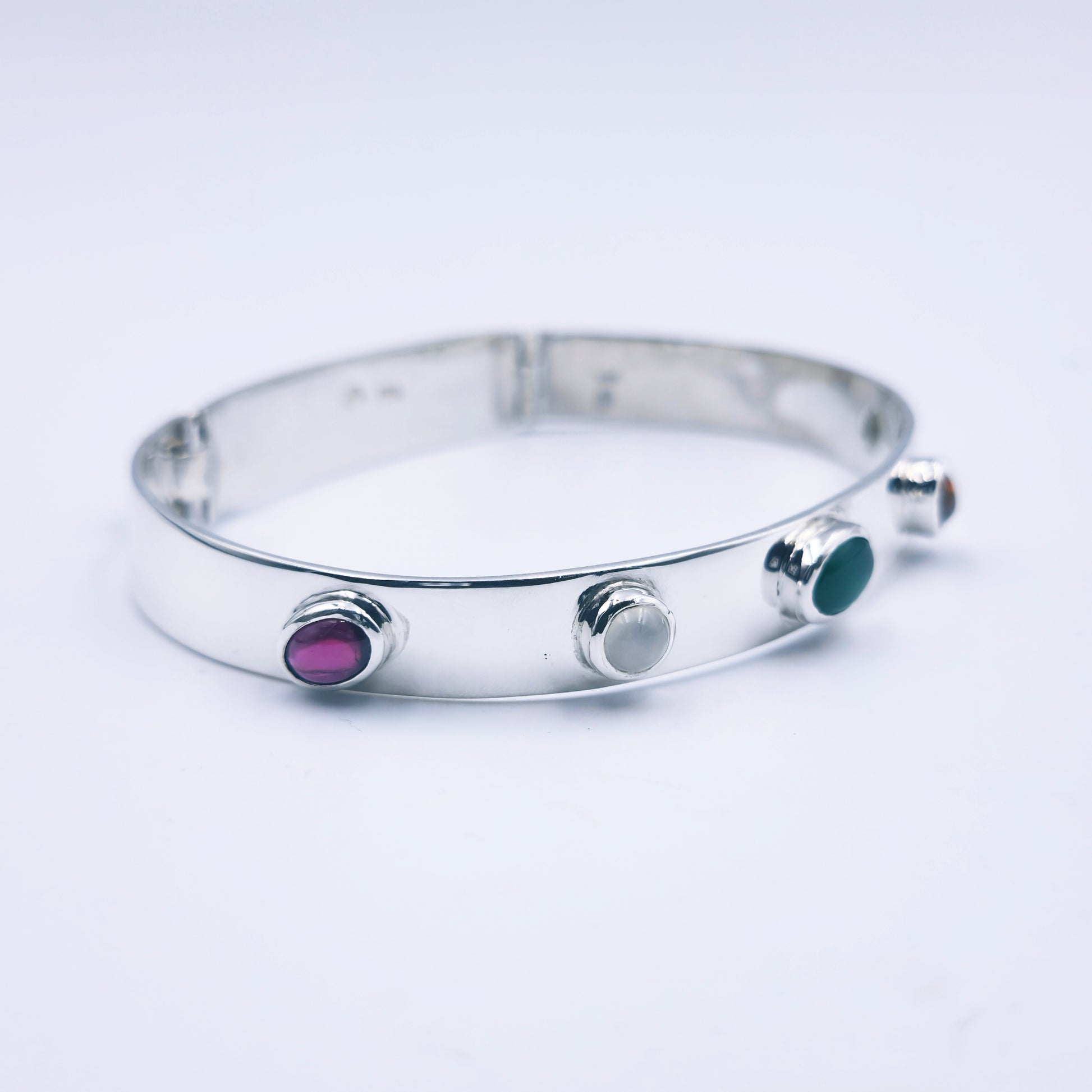 Sterling silver bangle with sky blue topaz, citrine, amethyst, peridot, and garnet in assorted cuts on a half-round band.