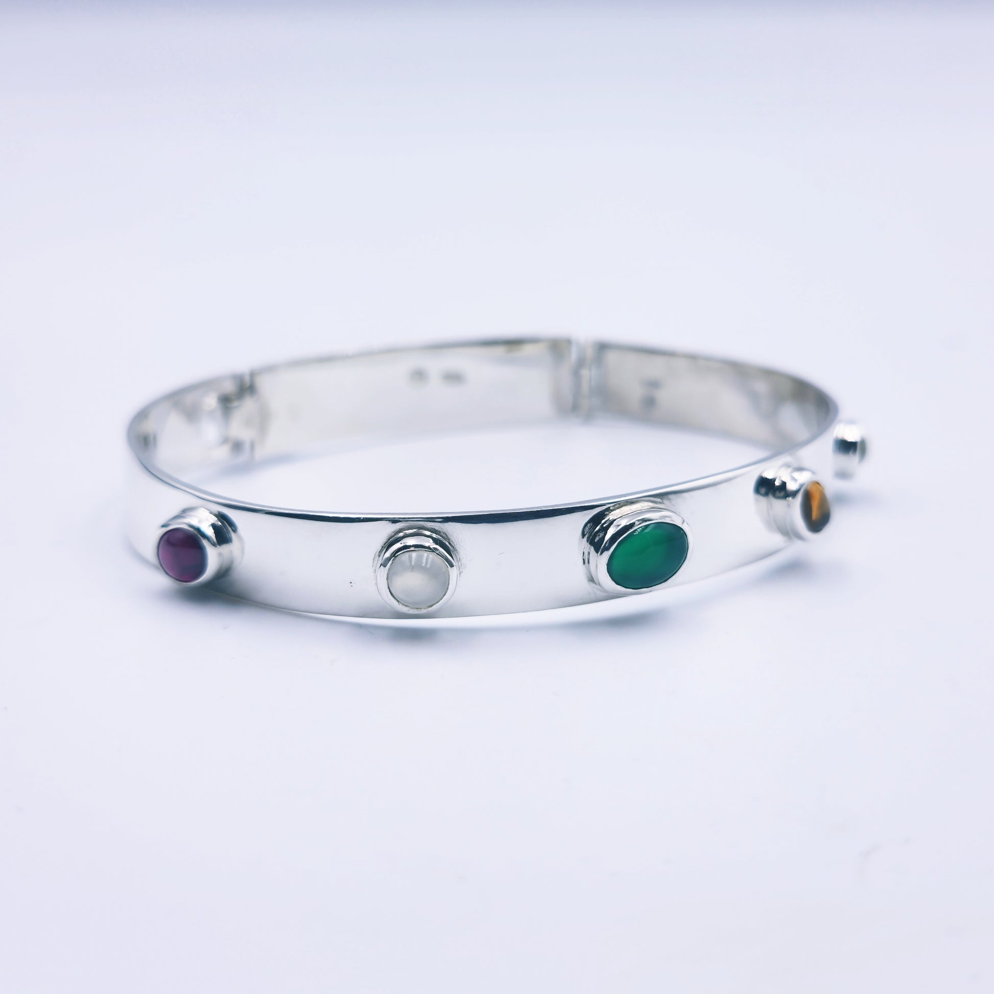 Sterling silver bangle with sky blue topaz, citrine, amethyst, peridot, and garnet in assorted cuts on a half-round band.