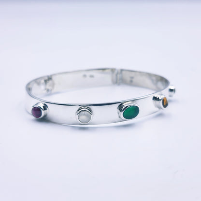 Sterling silver bangle with sky blue topaz, citrine, amethyst, peridot, and garnet in assorted cuts on a half-round band.