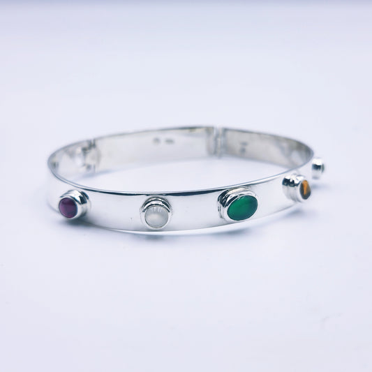 Sterling silver bangle with sky blue topaz, citrine, amethyst, peridot, and garnet in assorted cuts on a half-round band.
