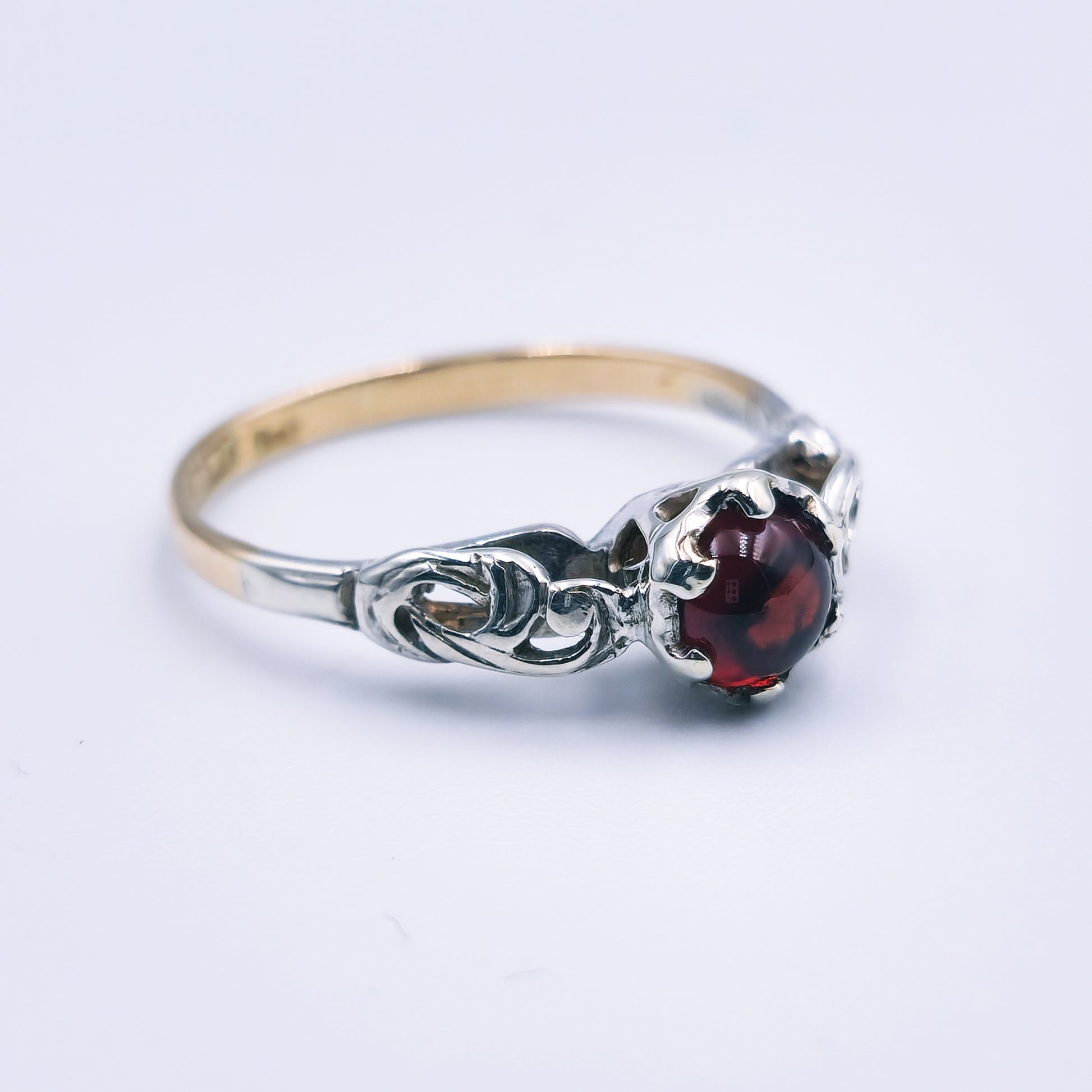 Two-toned 9ct gold ring with a 6mm cabochon cut garnet and detailed white gold accents.